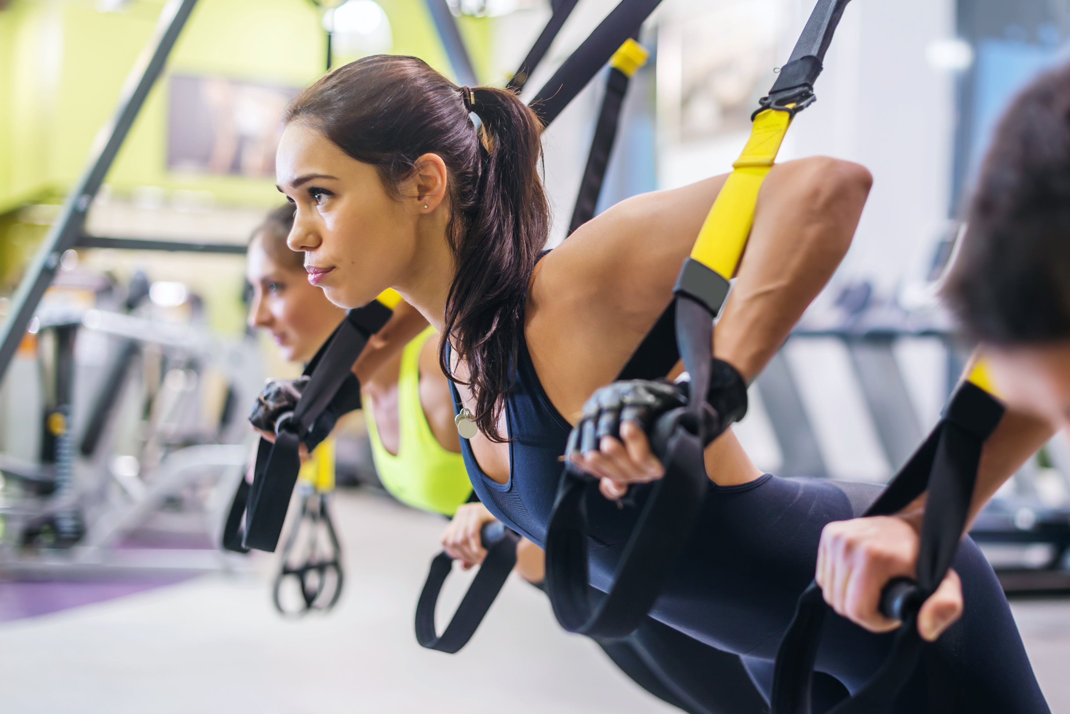 Women doing push ups training arms with trx fitness straps